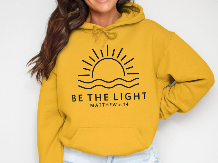 Yellow hoodie with sun and waves graphic, "Be The Light Matthew 5:14" text.