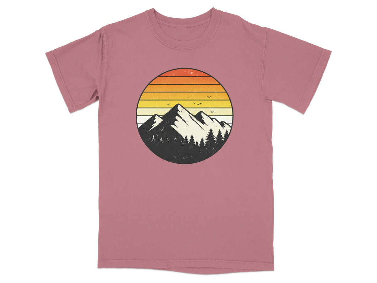 Circular mountain and forest graphic with sunset stripes on a rose t-shirt.