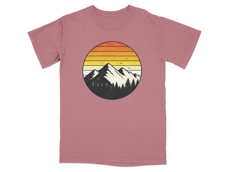 Circular mountain and forest graphic with sunset stripes on a rose t-shirt.