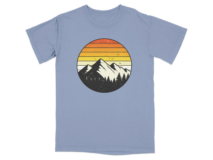 Retro mountain sunset graphic on a faded blue t-shirt.