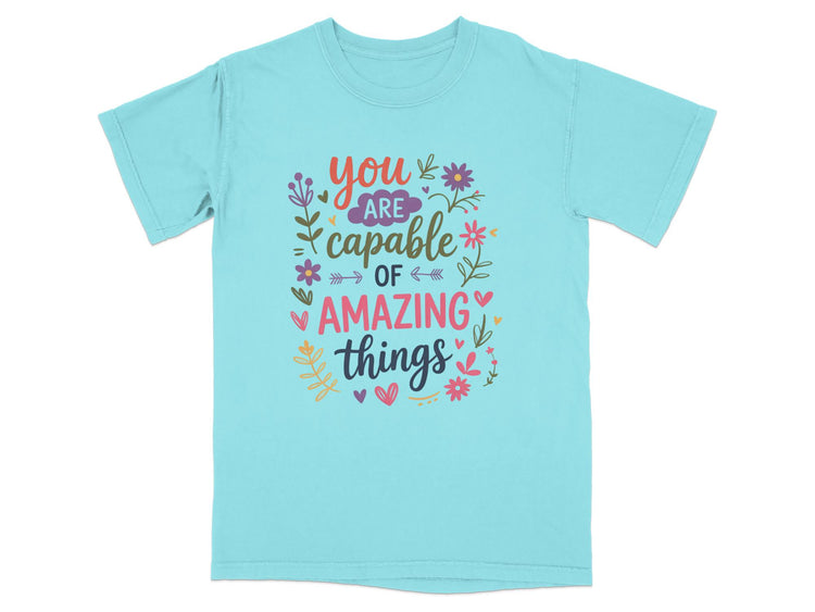 Teal t-shirt with "you are capable of amazing things" text and floral design.