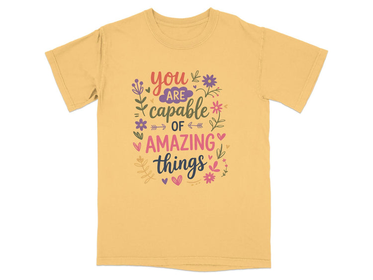 Yellow t-shirt with "you are capable of amazing things" text and floral accents.