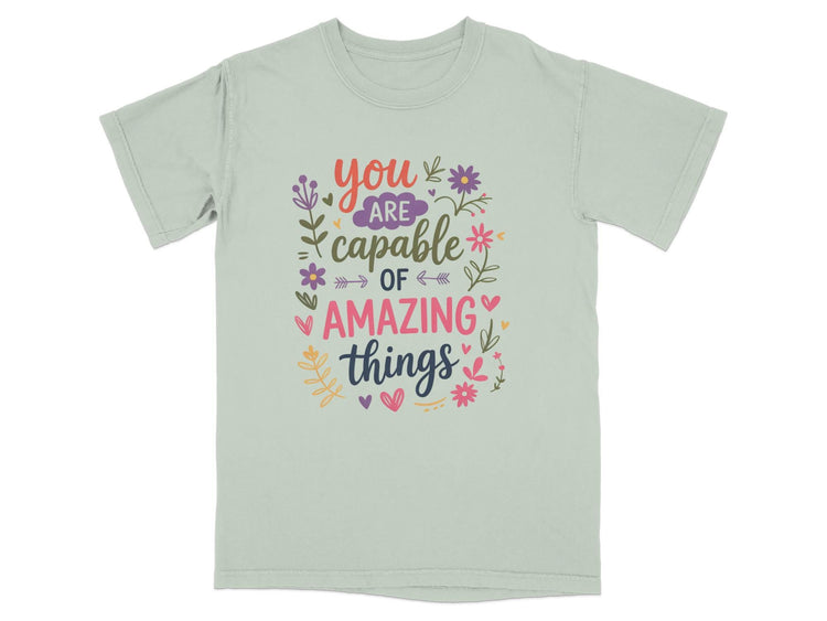 Light grey t-shirt with "You are capable of amazing things" text and floral accents.