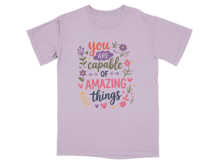 Purple t-shirt with "You are capable of amazing things" text and floral design.