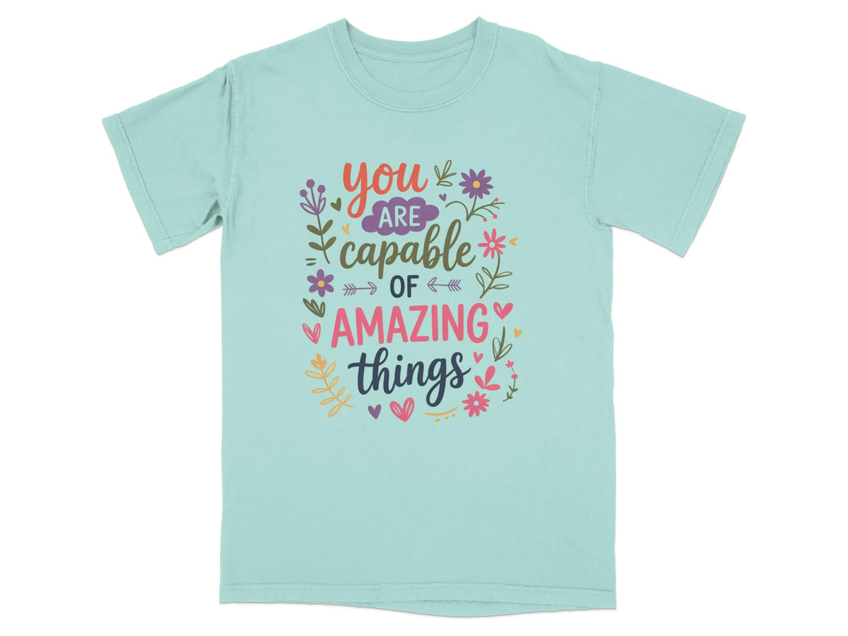 Mint green t-shirt with colorful text that reads "you are capable of amazing things."