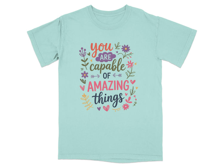 Mint green t-shirt with colorful text that reads "you are capable of amazing things."