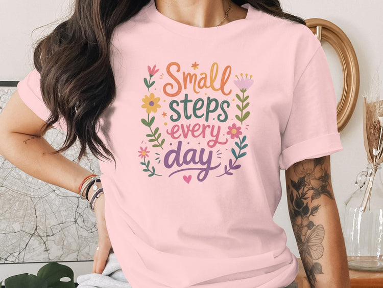 Pink t-shirt with "Small steps every day" and floral illustrations.