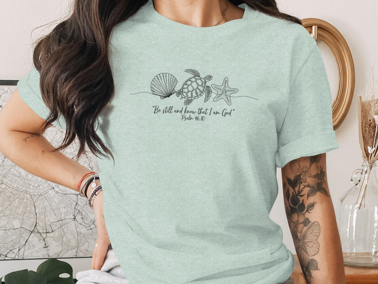 Light blue t-shirt with sea shell, starfish, and turtle line art and scripture.