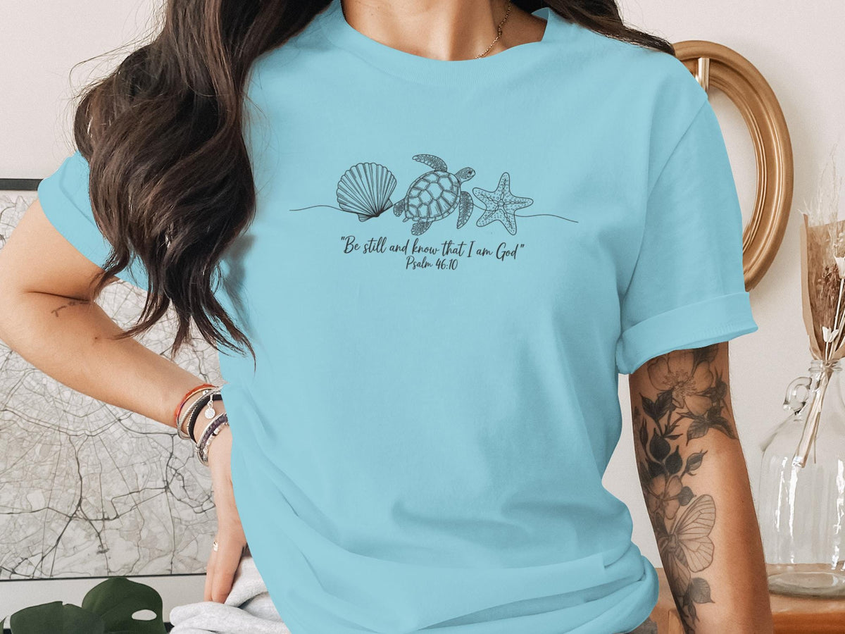Light blue t-shirt with seashells, starfish, and Psalm 46:10 quote.