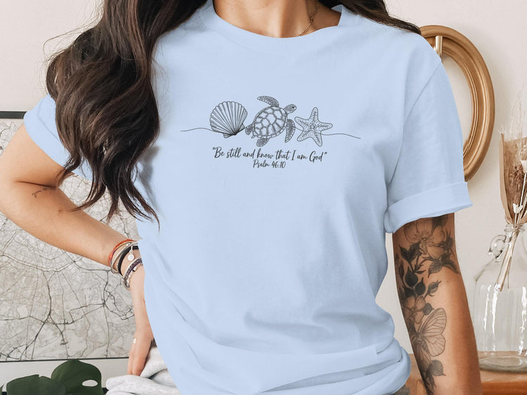 Light blue t-shirt with line art of a starfish, seashell, and turtle.