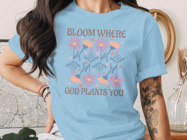 Light blue t-shirt with floral design and text "Bloom Where God Plants You".