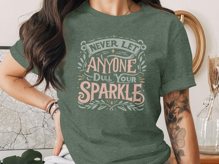 Woman wearing dark green t-shirt with "Never Let Anyone Dull Your Sparkle" text.