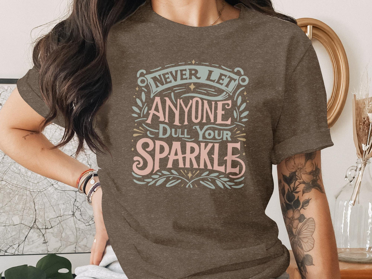 Brown t-shirt with "Never Let Anyone Dull Your Sparkle" text in colorful lettering.