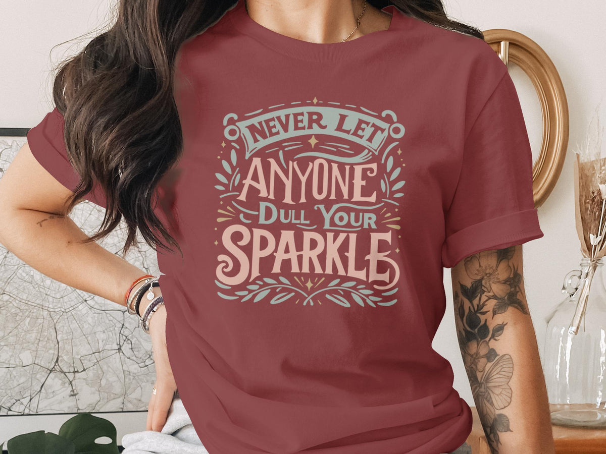 Maroon t-shirt with "Never Let Anyone Dull Your Sparkle" text and decorative elements.