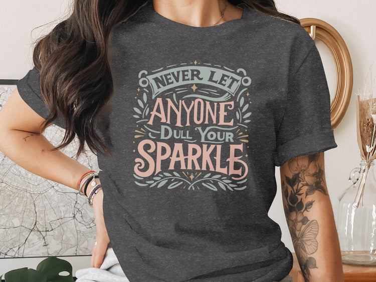 T-shirt with text "Never let anyone dull your sparkle" in decorative font.