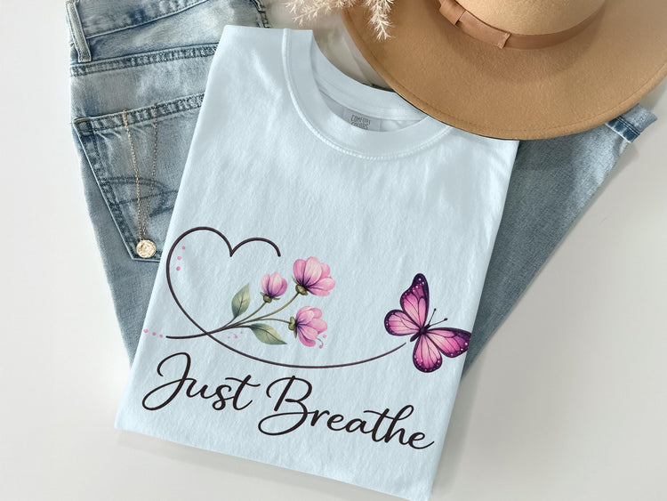 Light blue t-shirt with floral heart, butterfly, and "Just Breathe" text.