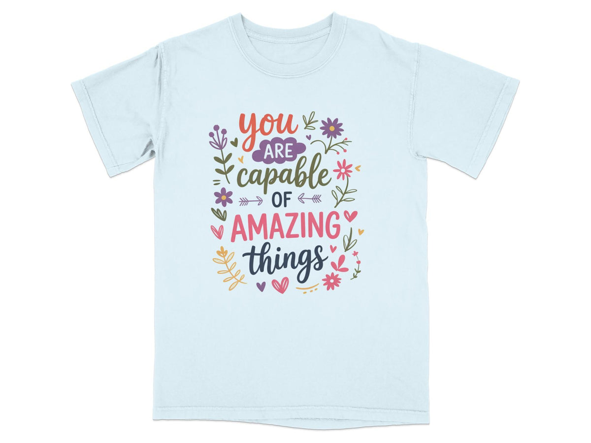 Light blue t-shirt with "you are capable of amazing things" text and floral accents.