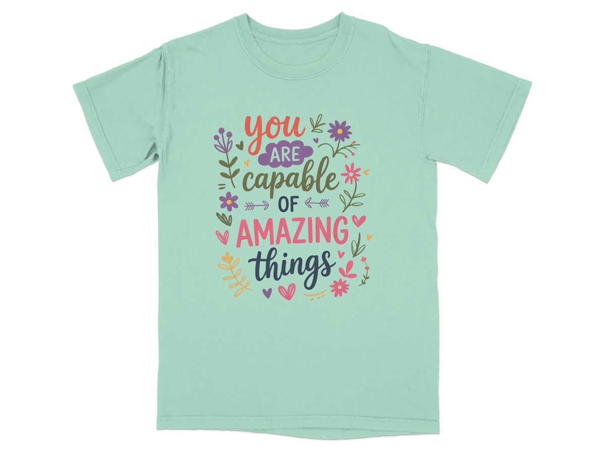 Mint t-shirt with colorful text reading "You are capable of amazing things."