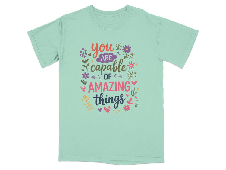 Mint t-shirt with colorful text reading "You are capable of amazing things."