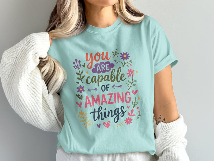 Light blue t-shirt with "you are capable of amazing things" text and floral accents.