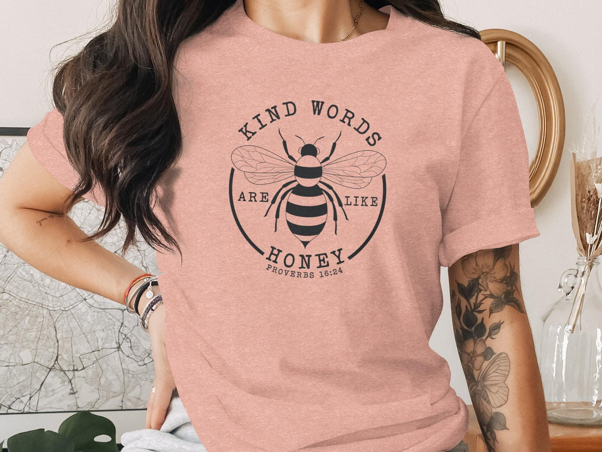 Pink t-shirt with a bee graphic and the text "Kind words are like honey Proverbs 16:24".