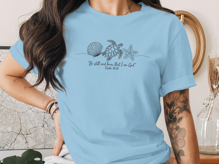 Light blue t-shirt with seashell, starfish, and turtle line art and text.