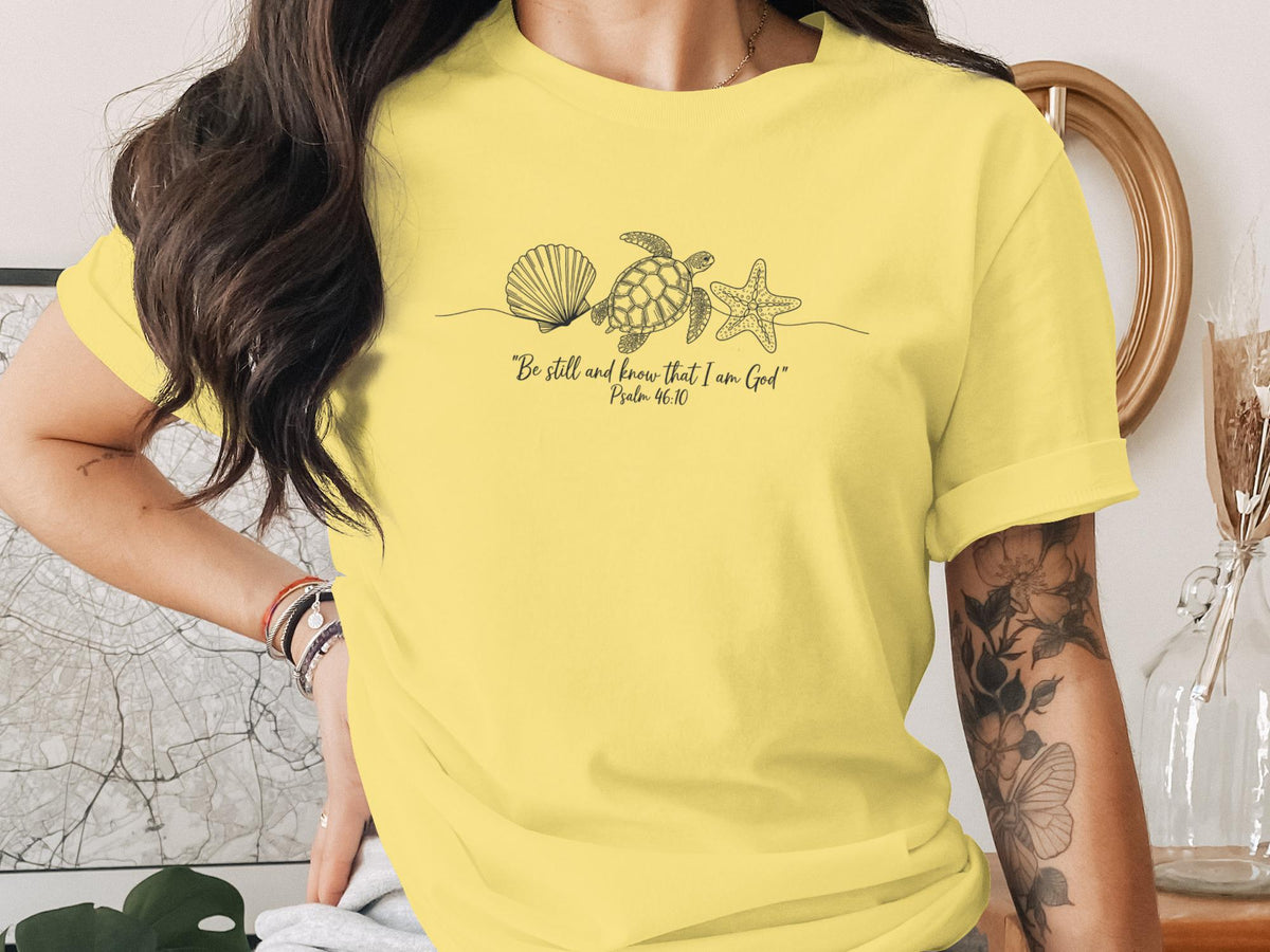 Yellow t-shirt with line drawing of seashell, starfish, turtle, and text.