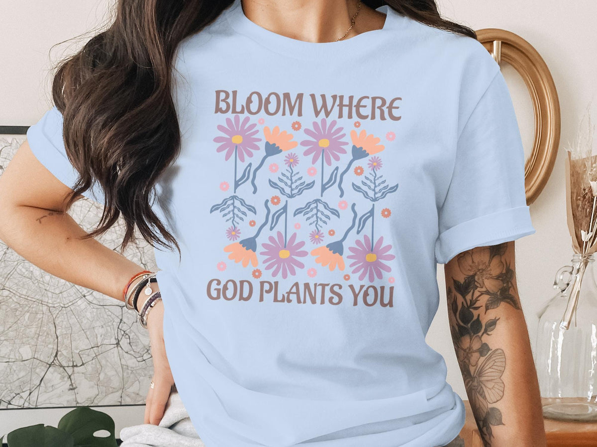 Light blue t-shirt with pastel flowers and text "Bloom Where God Plants You".