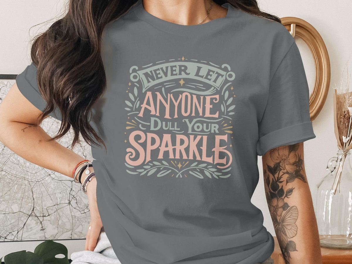Grey t-shirt with "Never Let Anyone Dull Your Sparkle" text design.