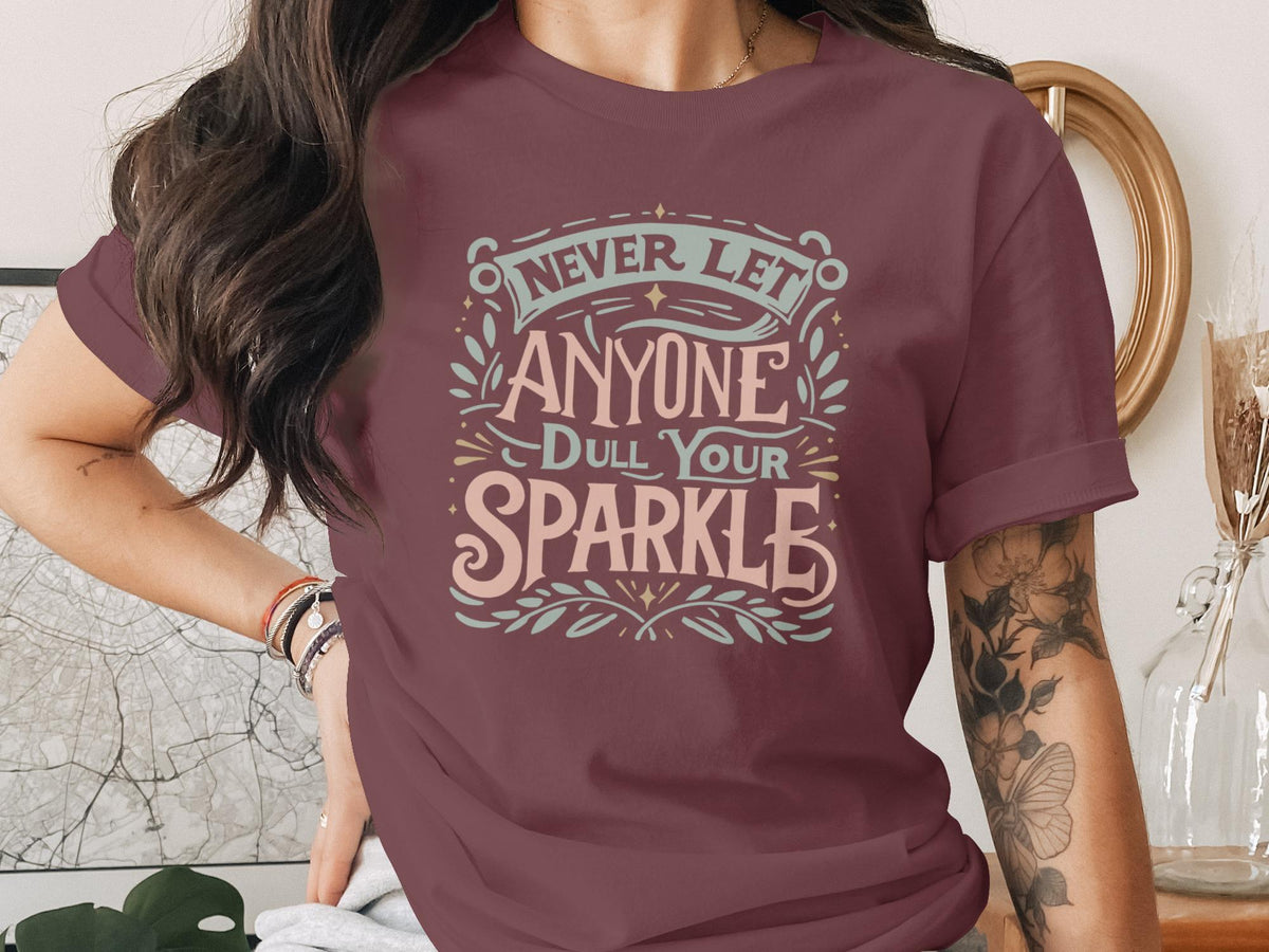 Burgundy t-shirt with "Never Let Anyone Dull Your Sparkle" text design.