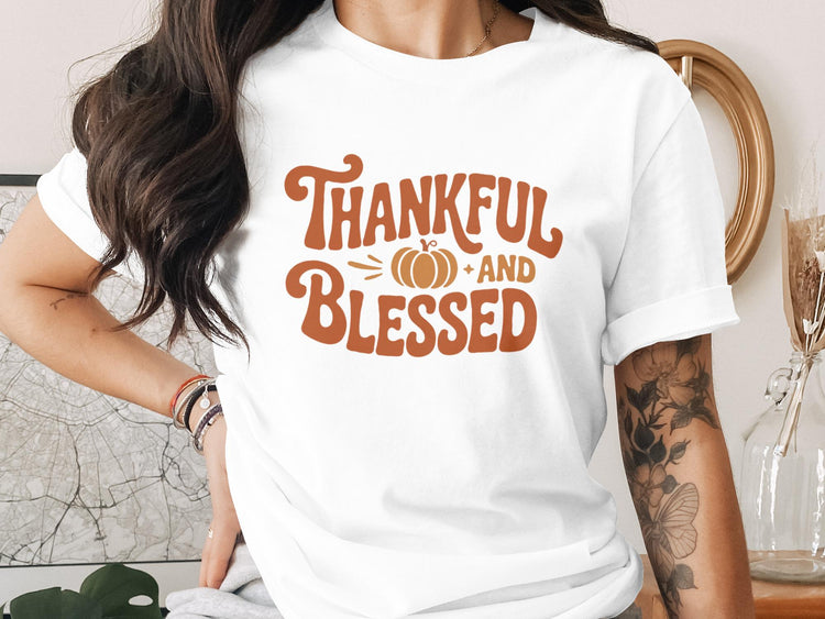 White t-shirt with brown text "Thankful and Blessed" and a pumpkin graphic.
