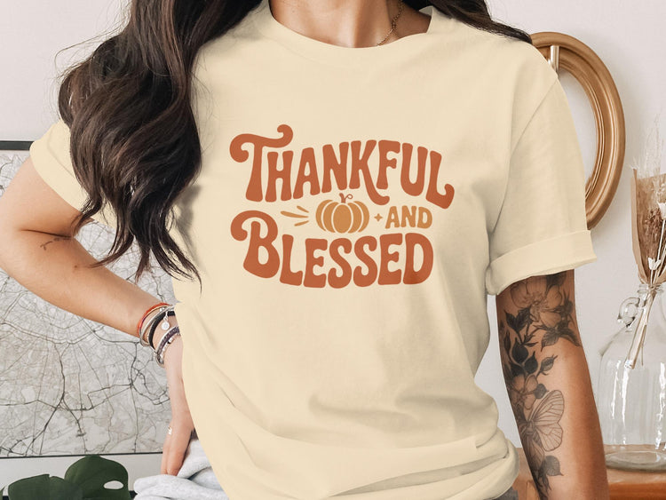 Cream t-shirt with orange graphic text "Thankful AND Blessed" and a pumpkin icon.