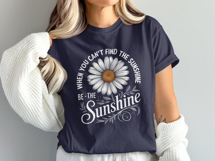 Navy t-shirt with white daisy graphic and text "WHEN YOU CAN'T FIND THE SUNSHINE BE-THE SUNSHINE"