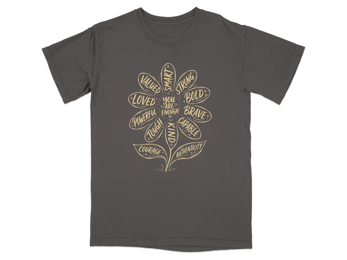 Grey t-shirt with a flower design listing positive affirmations such as "loved," "strong," and "brave."