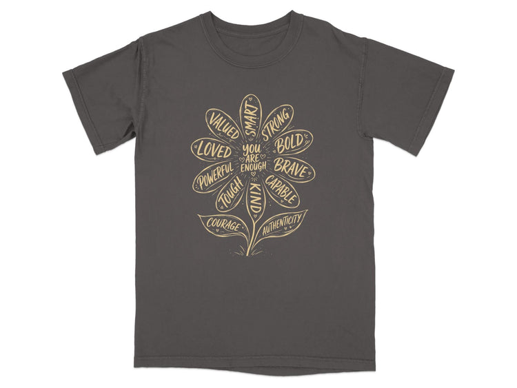 Grey t-shirt with a flower design listing positive affirmations such as "loved," "strong," and "brave."