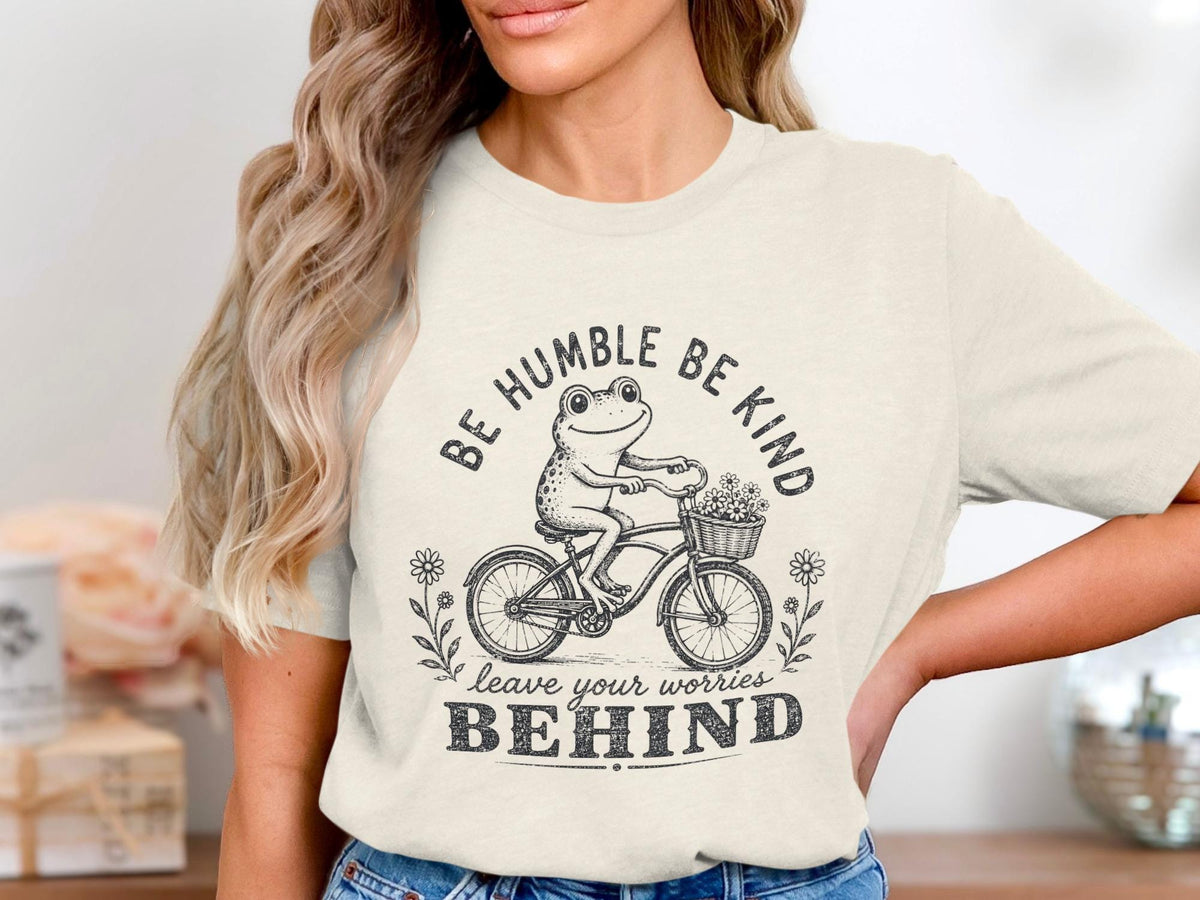 Frog on bicycle with flower basket, "BE HUMBLE BE KIND LEAVE YOUR WORRIES BEHIND."
