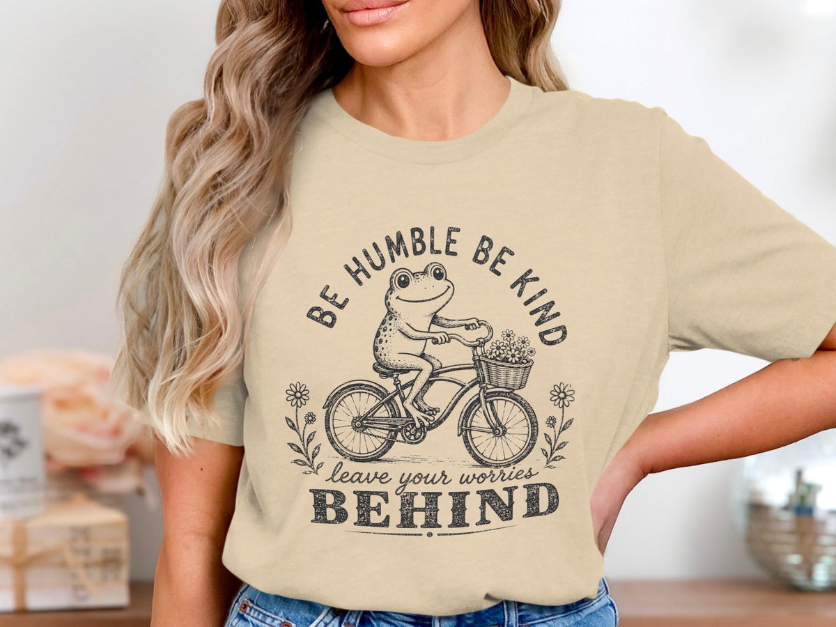 Frog riding bicycle with flowers, "Be Humble Be Kind" and "Leave Your Worries Behind" text.