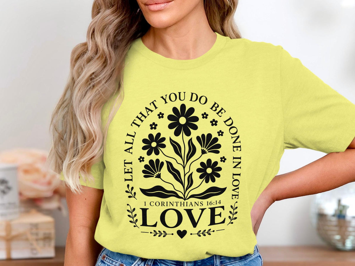Yellow t-shirt with black floral design and text "Let all that you do be done in love."