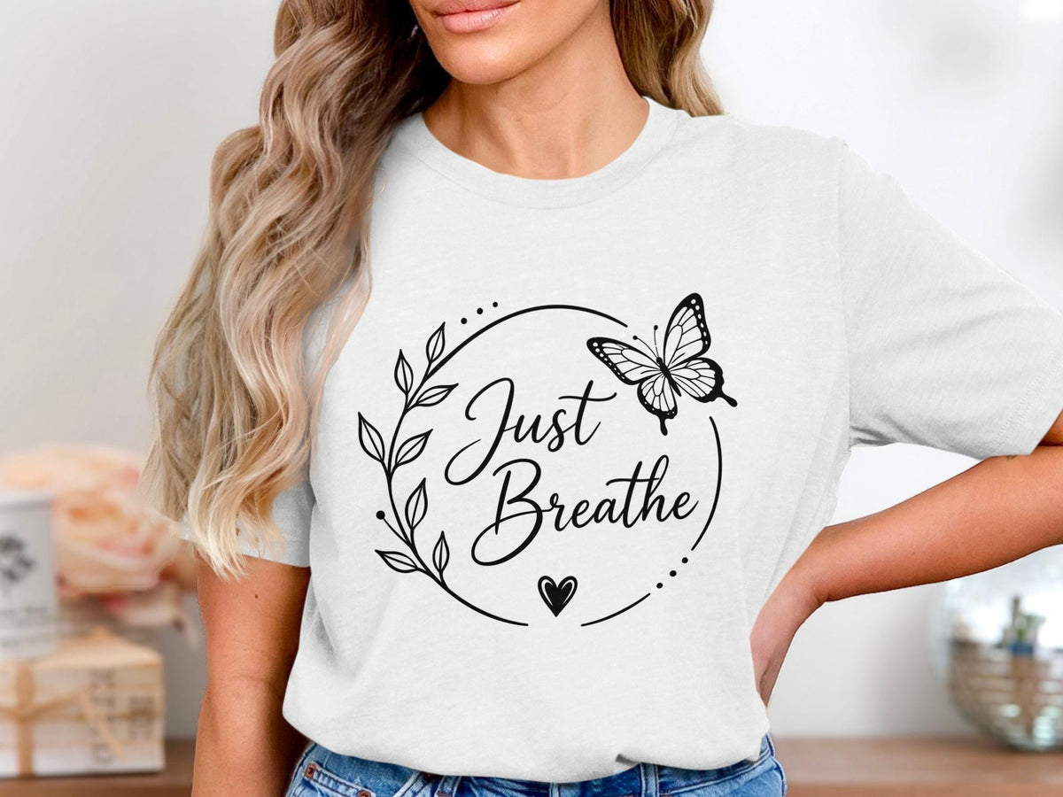 White t-shirt with black "Just Breathe" text, butterfly, and floral wreath.