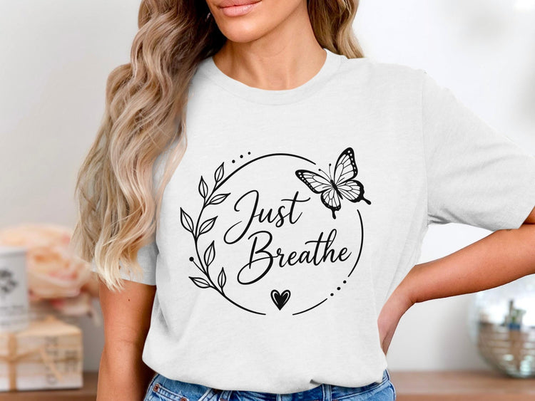 White t-shirt with black "Just Breathe" text, butterfly, and floral wreath.