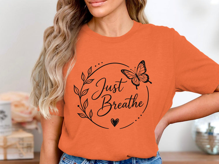 Orange t-shirt with black butterfly and leaf graphic reading "Just Breathe".