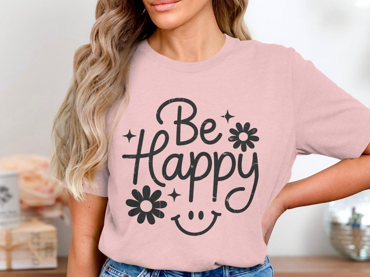 Pink t-shirt with distressed black "Be Happy" text, flowers, stars, and smiley face.