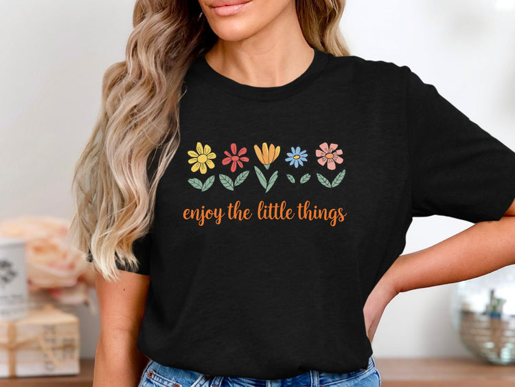 Black t-shirt with colorful flowers and "enjoy the little things" text.