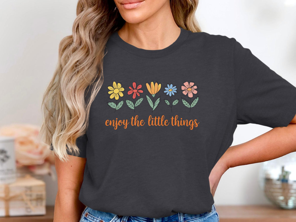 Dark grey t-shirt with colorful flowers and orange text that says "enjoy the little things".