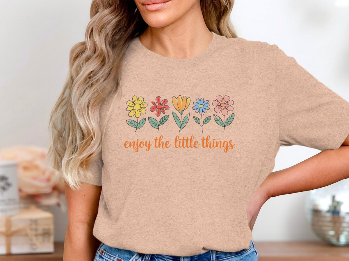 Peach t-shirt with a line of colorful flowers and the text "enjoy the little things".