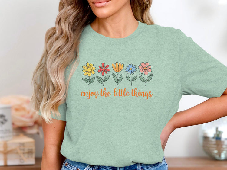 Mint green t-shirt with line-drawn flowers and "enjoy the little things" text.
