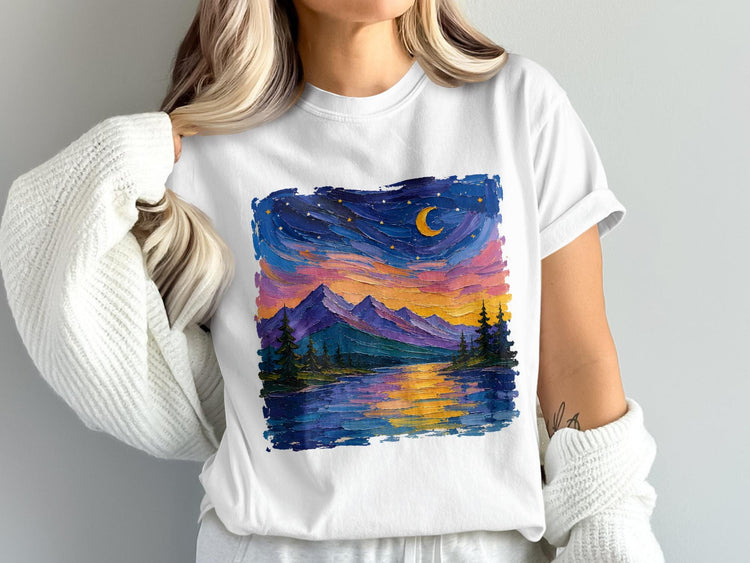 White t-shirt with a vibrant, textured painting of a mountain lake under a starry night sky.