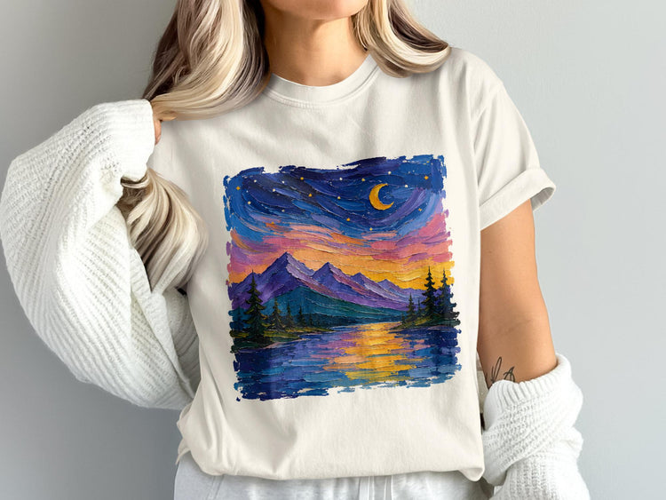 White t-shirt with painted landscape of mountains, trees, and a moonlit sky.