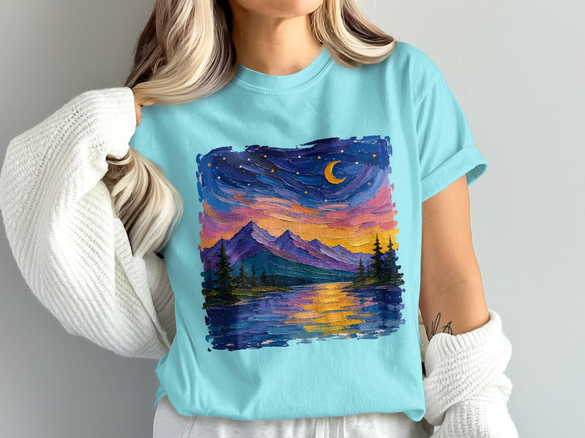 Light blue t-shirt featuring a colorful, textured landscape print of mountains, trees, and a moonlit sky reflects on water.