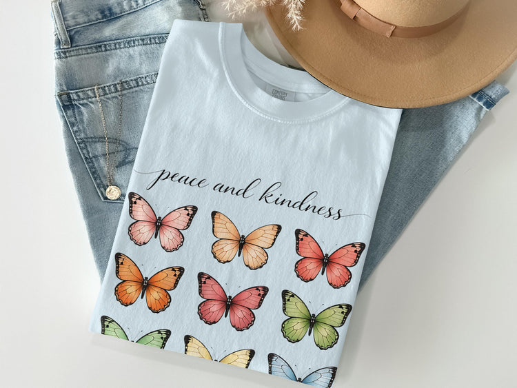 Light blue t-shirt with "peace and kindness" text and colorful butterflies.